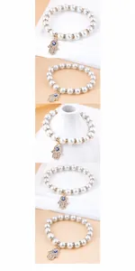 Detail of beaded pearl bracelet featuring Hamsa Hand pendant and blue Evil Eye charm