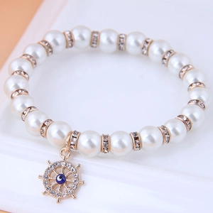 Elegant beaded bracelet with white pearls, golden ship wheel charm and blue Evil Eye motif
