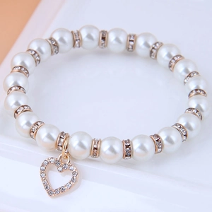 Close-up of beaded pearl bracelet featuring a crystal-studded hollow heart pendant