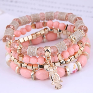 Detailed close-up of multi-layer beaded bracelets with pink beads and owl charm