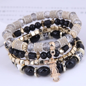 Macro shot of owl charm bracelet with patterned beads and layered metallic accents