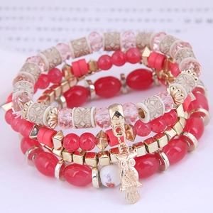 Detail of four-piece layered bracelet set with colorful beads and golden owl charm