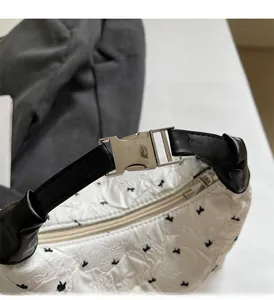 Close-up of white handbag with black bow patterns, leather handle and silver buckle