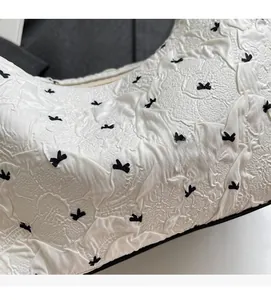 Close-up of white crinkled fabric featuring a dense black bow pattern and soft texture