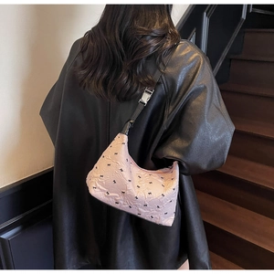 Detail of pink shoulder bag featuring black bow embroidery and silver metal buckle