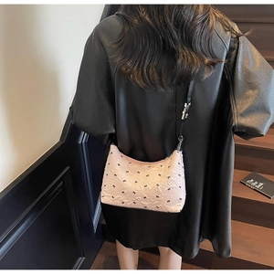 Detailed shot of pink bow-print shoulder bag showing fabric texture and black strap
