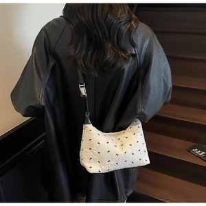 Detail of white quilted half-moon bag with black patterns and adjustable leather strap