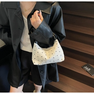 Detail of white half-moon handbag featuring embossed floral patterns and metal zipper