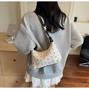 Close-up of white half-moon bag featuring black bow patterns and adjustable shoulder strap