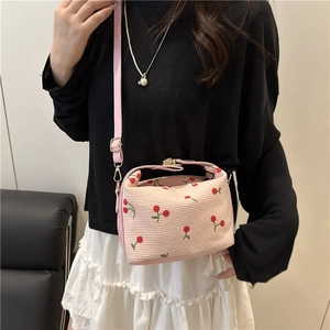 Pink cherry print crossbody bag with metal lock and adjustable strap on a female model