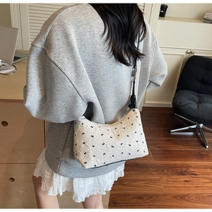 Detailed texture of white embossed fabric on the shoulder bag with black bow patterns