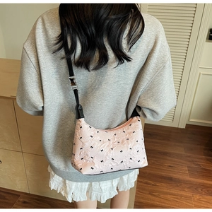Detail of pink shoulder bag with black bow patterns and pleated texture on model
