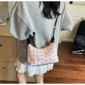 Detail of pink bow-patterned shoulder bag showing ruffled texture and adjustable strap