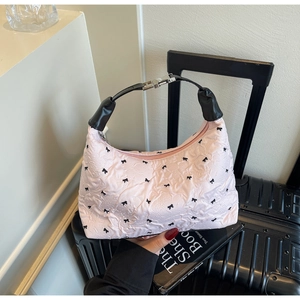 Close-up of pink pleated handbag with bow embroidery and black leather strap details