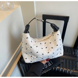 Detail of white wrinkled fabric with black bow embroidery and leather handle on a bag