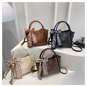 Detail of four chic bucket bags in caramel, black, beige and coffee with silk scarves