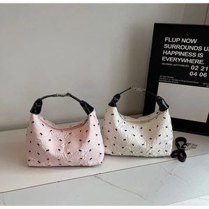 Detail of pink and white polka dot hobo bags with black bow embroidery and quilted texture