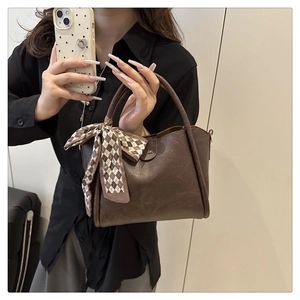 Detail of vintage brown PU tote bag with litchi texture and elegant silk scarf handle