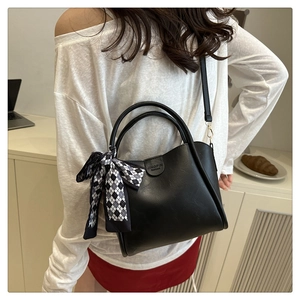 Close-up of black PU leather handbag with decorative checkered silk scarf and logo