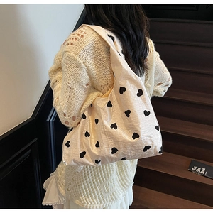 Détail du sac cabas crème avec motifs de cœurs noirs et texture de tissu plissé