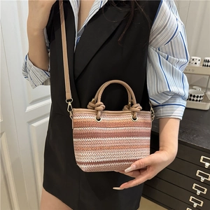 Straw beach bag with earthy striped woven pattern, leather handles, and shoulder strap