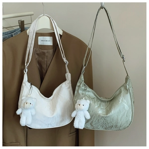 Detail of pleated satin texture shoulder bags in white and green with plush bear charm