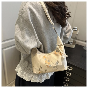 Detail of elegant Chinese style floral embroidery on a cream canvas shoulder bag texture