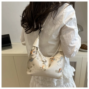 Detail of beige hobo bag with traditional Chinese floral and bird embroidery on shoulder