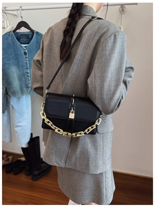 Détail du sac à bandoulière en cuir mat noir avec chaîne dorée et boucle à cadenas