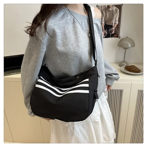 Vue latérale d'un sac à bandoulière en toile noire à rayures blanches pour le quotidien