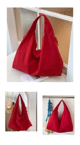 Detail of red oversized hobo tote bag featuring drawstring accents and textured fabric