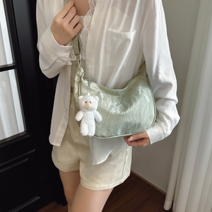 Sage green pleated shoulder bag with cute plush bear charm in a stylish daily look