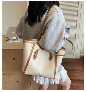 Rear view of a large two-tone faux leather tote bag worn by a model in a modern office setting