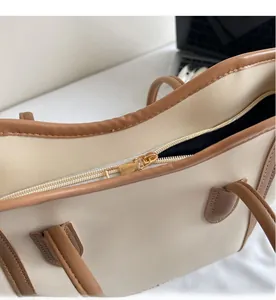 Close-up of smooth golden metal zipper detail on a minimalist two-tone leather tote bag