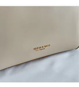Close-up of cream leather tote bag featuring gold embossed FASHION & BAGS lettering