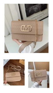 Detalle del bolso beige con patrón de cocodrilo, logo M dorado y correa de cadena