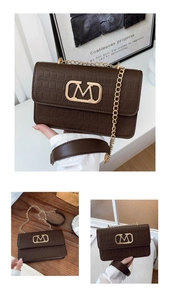 Detalle del bolso bandolera marrón con grabado de cocodrilo y hebilla metálica dorada en M