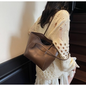 Model wearing a large vintage brown tote bag on a staircase in a modern indoor setting