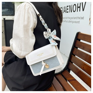 Détail du sac à bandoulière blanc et bleu avec texture gaufrée et poignée en foulard