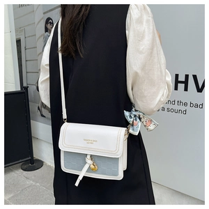 Detail of color-block square bag with woven texture, silk scarf and gold metal pendant