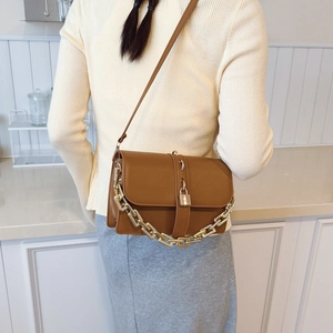Sac bandoulière en cuir marron avec chaîne dorée et cadenas sur un mannequin