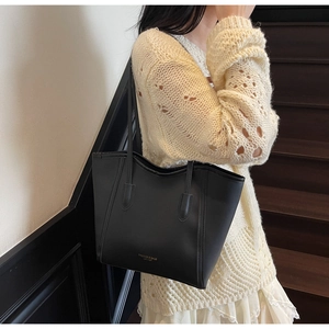 Close-up of black leather tote bag featuring gold FASHION & BAGS lettering on the surface