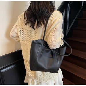 Close-up of minimalist black matte tote bag with elegant gold logo and leather texture