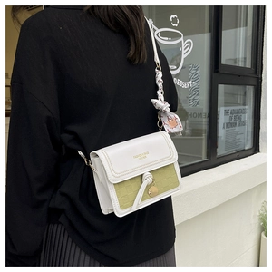 Detail of crossbody bag with green texture, white flap, knot detail and silk scarf