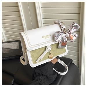 Détail du sac à bandoulière tissé blanc et vert avec foulard en soie et pendentif doré