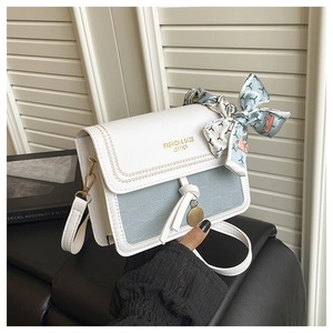 Détail du rabat en cuir blanc avec texture tissée bleue et foulard décoratif en soie