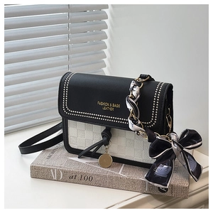 Detail of black and white square bag with metal rivets and decorative silk scarf wrap