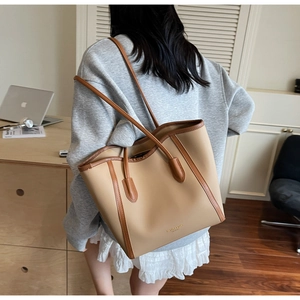 Close-up of beige tote bag with brown straps in a cozy home office setting