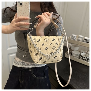 Detail of beige leather bucket bag featuring a cartoon bear print and silver chain strap