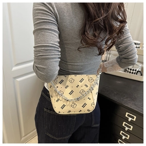 Detail of cream crossbody bag with black bear print and silver metal chain decoration